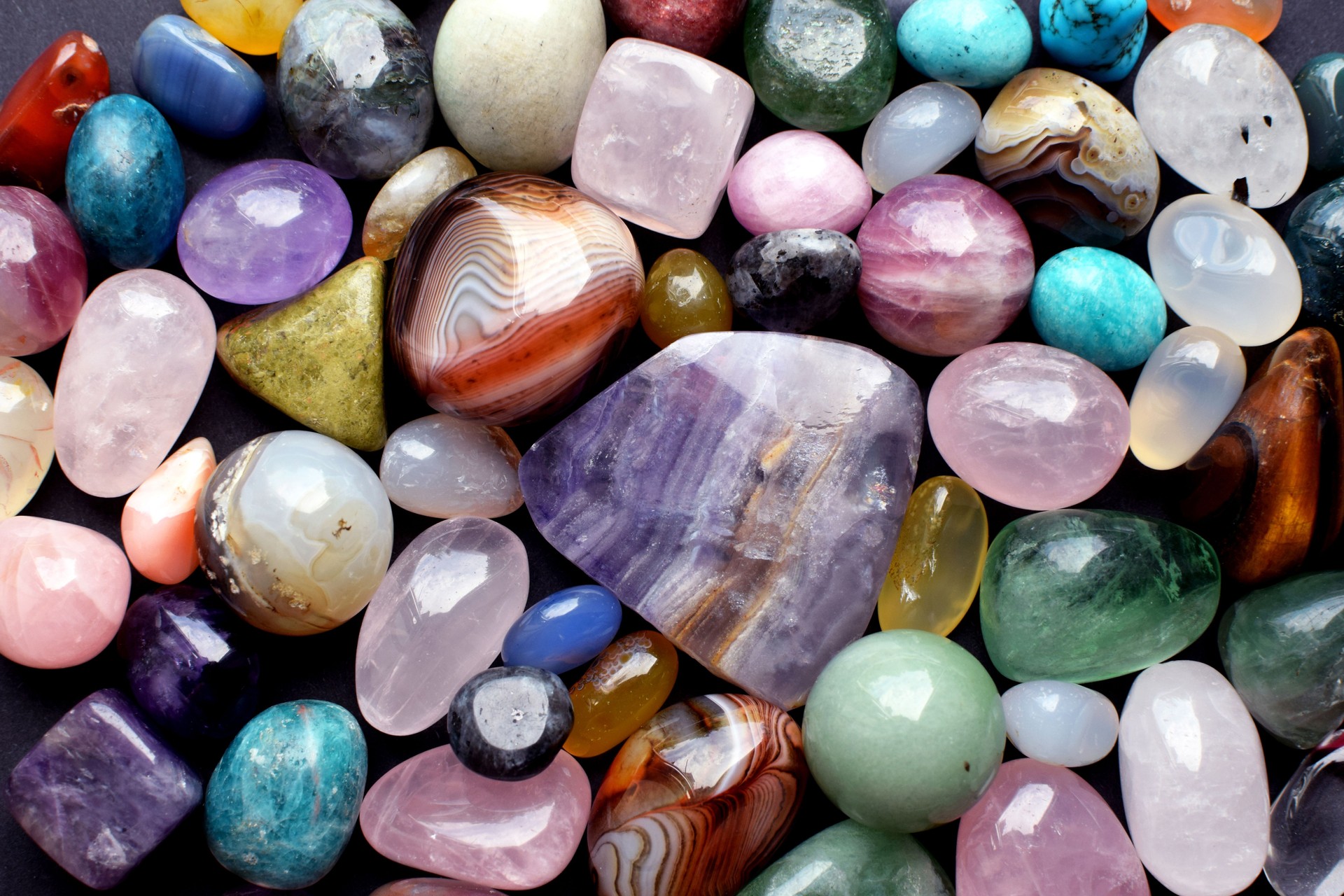 Background made of beautiful natural colored semi-precious stones. Purple fluorite, rose quartz and agate close-up.