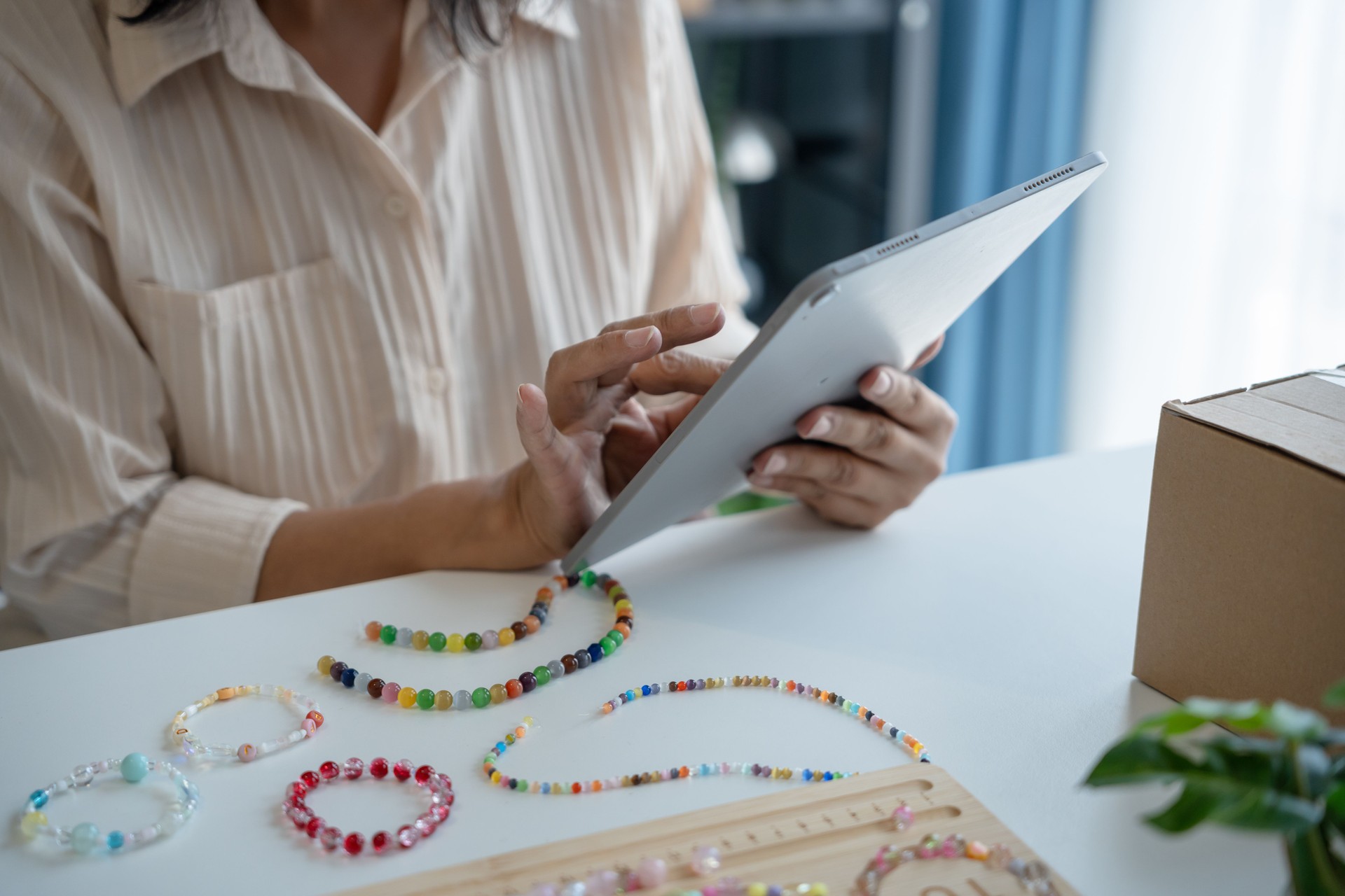 Mature asian womanÂ business ownerÂ E-commerce online orders with tablet entrepreneurship jewellery accessories handcraft Cardboard Box.